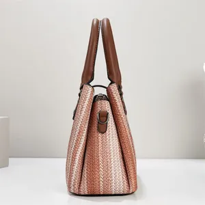 Side view of a striped woven handbag featuring brown faux leather handles and metal hardware