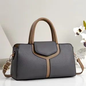 Gros plan d'un sac à main tendance en patchwork gris et marron avec texture cuir grainé.