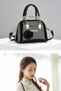 Elegante borsa in vernice nera con ciondolo a forma di rosa, mostrata da modella in qipao