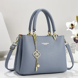 Elegant blue leather handbag with gold-tone hardware and detailed decorative charm detail