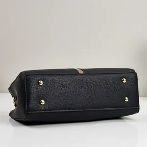 Vue de dessous d'un grand sac à main noir avec quatre clous en métal doré pour protection