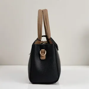 Vue latérale d'un sac à main en cuir grainé avec poignées bicolores et détail d'anneau