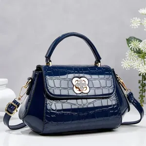 Elegante bolso azul marino con patrón de cocodrilo y cierre de trébol dorado de cerca
