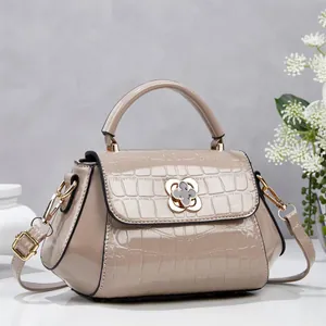 Detalle de la textura de cocodrilo y el cierre floral dorado en el bolso bandolera nude.