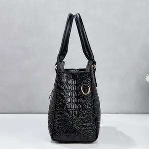 Side profile of a black crocodile pattern handbag featuring elegant gold hardware detail.