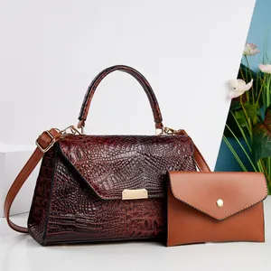 Vista dettagliata della borsa marrone con trama a coccodrillo e pochette abbinata.