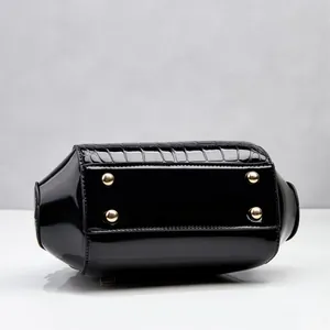 Vista inferior del bolso negro con diseño de cocodrilo y pies dorados