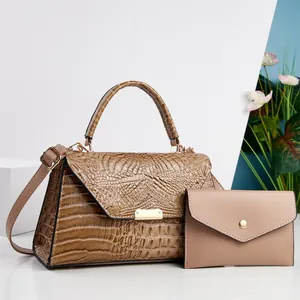 Vista dettagliata di un set di borse marroni con motivo a coccodrillo e pochette