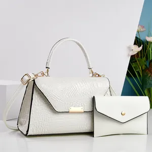 Dettaglio ravvicinato della borsa a mano in coccodrillo bianco e pochette con hardware oro.