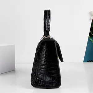 Vista laterale di una borsa nera con trama a coccodrillo e manico superiore robusto.