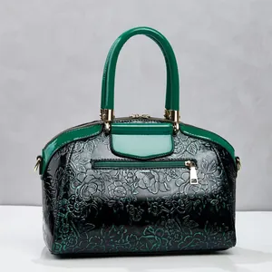 Elegante dunkelgrüne Handtasche mit Blumenprägung, glänzenden Griffen und Golddetails