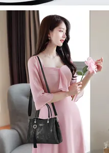 Elegant black textured handbag with tassel charm and shoulder strap shown on a model.