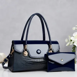 Détail d'un ensemble de sacs à main bleu marine avec motif crocodile et pochette assortie.