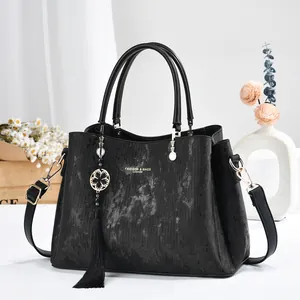 Elegant black textured leather handbag for women featuring a tassel and flower charm