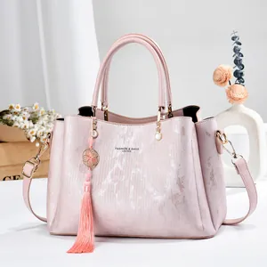 Elegant pink textured leather handbag with tassel charm, top handle, and shoulder strap
