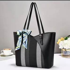 Side view of a large black tote bag featuring a striped panel and decorative silk scarf
