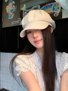 Close-up of a vintage beige checked octagonal newsboy hat worn by a female model.