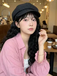 Chic Asian woman modeling a black grid patterned newsboy cap in a cozy cafe setting
