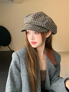 Asiatisches Model mit einer stylischen braun karierten Newsboy-Mütze im Retro-Design