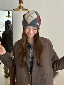 Close-up of a model wearing a vintage argyle knit beanie in grey and red autumn colors