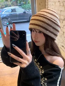 Stylish Asian woman wearing a retro brown and beige striped knitted beanie in a cafe