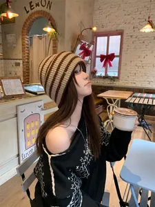 Model wearing a vintage striped knit beanie in a cafe, showing the slouchy winter fit
