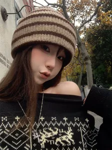 Stylish vintage striped knitted beanie hat worn by a model in a cozy outdoor autumn setting.
