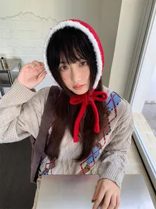 Close-up of red plush knitted hood with bow worn by a model in a cozy setting