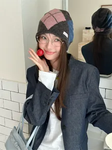 Detail shot of a stylish argyle plaid knitted slouchy beanie worn by a female model.