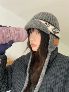 Close-up of vintage grey jacquard knit earflap hat worn by model with purple yarn detail