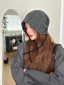 Model wearing a retro black and white plaid bonnet beanie with stylish black straps