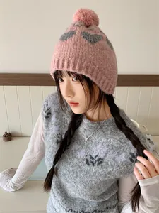 Stylish Asian model wearing a soft pink knitted beanie with pom-pom and grey heart patterns
