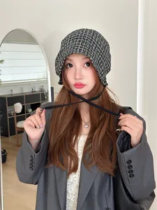 Asian model wearing a black and white checkered tie-front beanie hat for a retro look