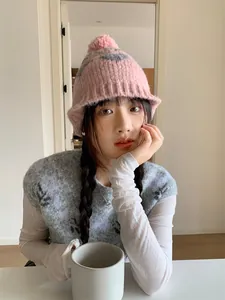 Close-up of a pink knitted hat with pom-pom and heart pattern on a model