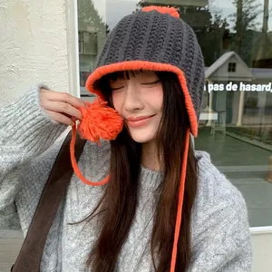 Fashionable gray and orange knitted earflap hat with cute pom-poms for winter wear
