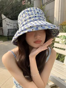 Blue checkered bucket hat with heart pattern worn by model in outdoor setting