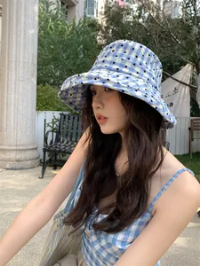 Detail view of a blue heart pattern gingham bucket hat on a model in an outdoor park