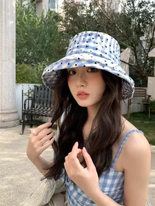 Close-up of blue checkered bucket hat with heart pattern on an outdoor model
