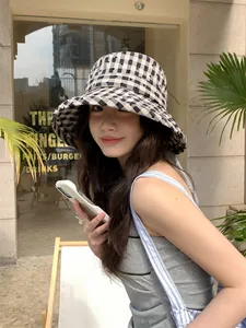 Detail shot of a stylish checkered bucket hat with heart patterns on a model in sunlight