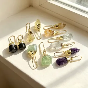 Detailed macro shot of natural raw crystal earrings in amethyst and citrine with gold hooks
