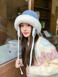 Asian model wearing a blue plush winter trapper hat with white fur trim and long ties