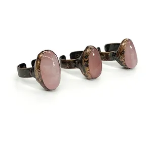 Close-up of vintage adjustable bronze rings with polished oval rose quartz stones.
