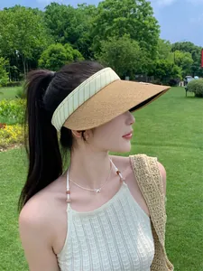 Primo piano di una donna che indossa una visiera in paglia in un rigoglioso parco verde.