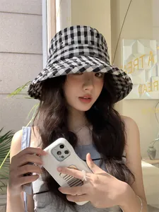 Fashionable young woman wearing a heart-patterned plaid bucket hat in a cafe setting