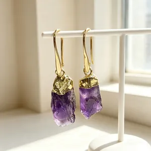 Detailed view of natural amethyst raw stone gold-plated drop earrings in soft light
