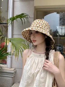Lifestyle view of woman wearing yellow checkered sun hat with black heart pattern