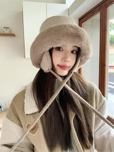 Close-up of a stylish beige plush bucket hat with earflaps worn by a model in winter.