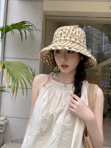 Close-up of stylish yellow gingham bucket hat with heart pattern in a cafe setting