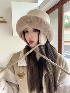 Close-up of a model wearing a thick plush winter earflap fisherman hat in beige