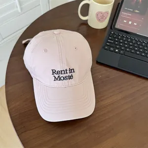 Casquette de baseball rose minimaliste avec broderie Rent in Mosté sur table en bois.